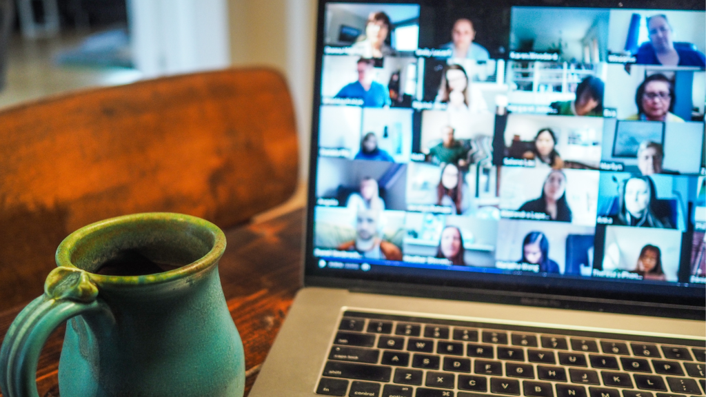 A mug next to a laptop with a group video chat playing